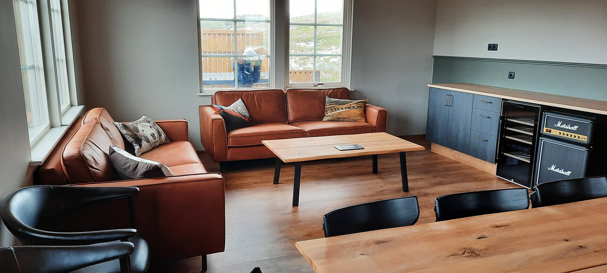 Lounge med läderfåtöljer och stora fönster i fiskelodgen på Island