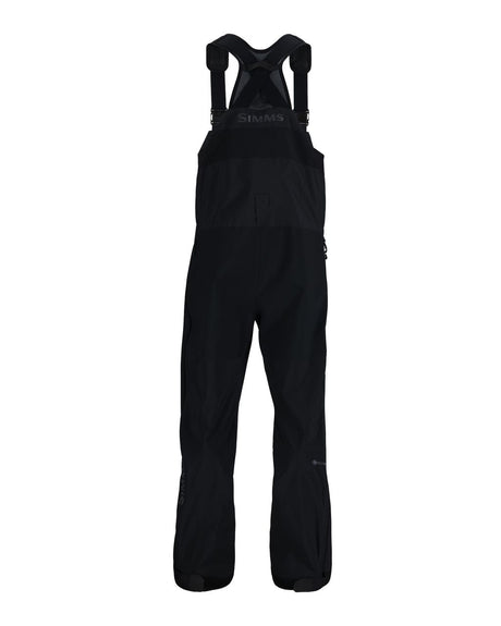Svart Simms Pro Dry fiskeoverall, vattentät med justerbara axelband, förstärkta knän och logga. Perfekt för fiskare.